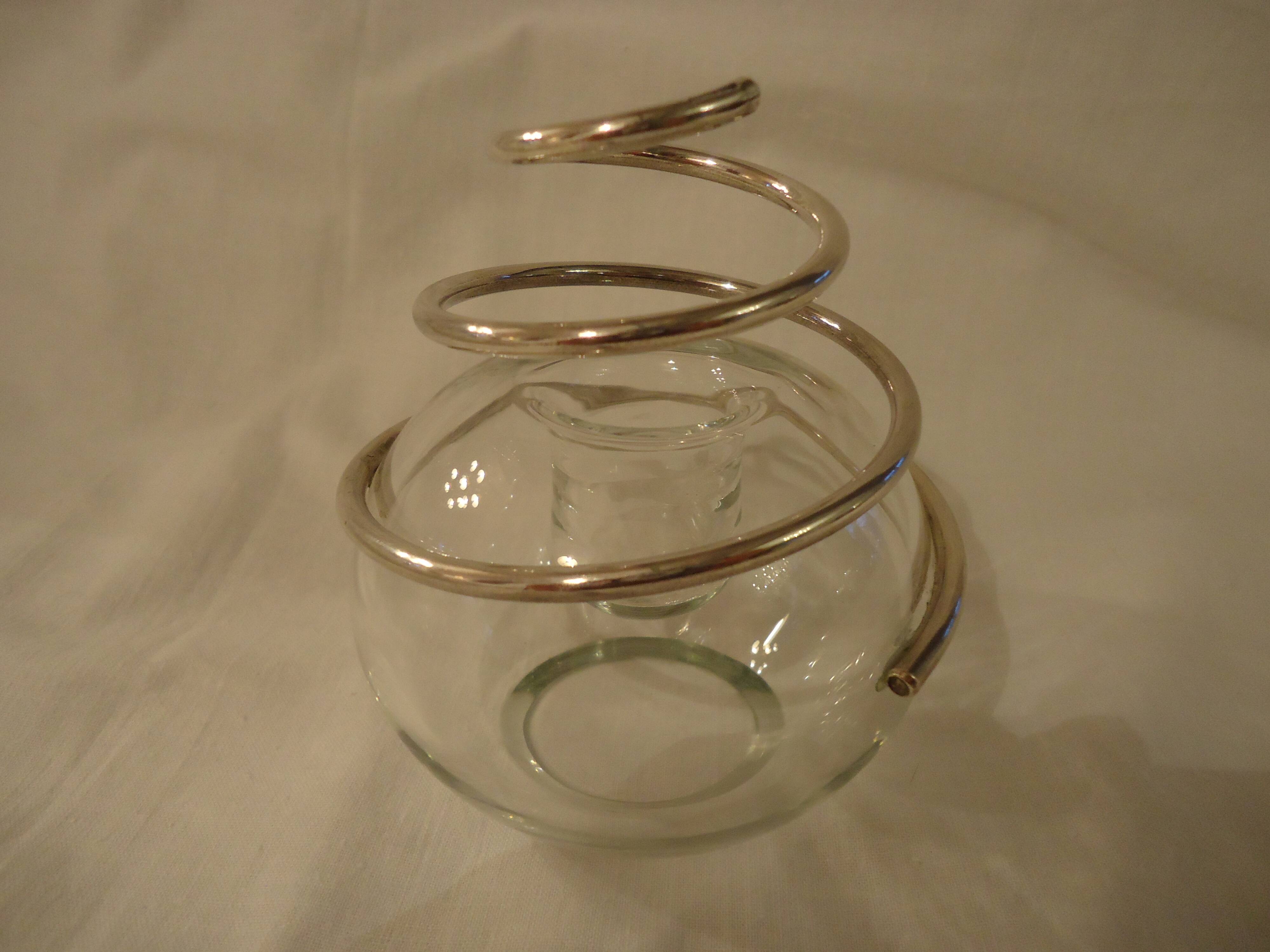 Round glass candle holder with silver-plated metal spiral.
