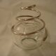 Round glass candle holder with silver-plated metal spiral.