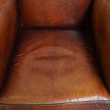 Sheepskin leather armchair in a cognac color with black piping