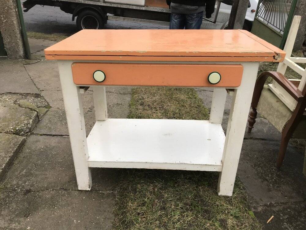 Vintage wooden kitchen table in orange and white with a drawer and low shelf.
