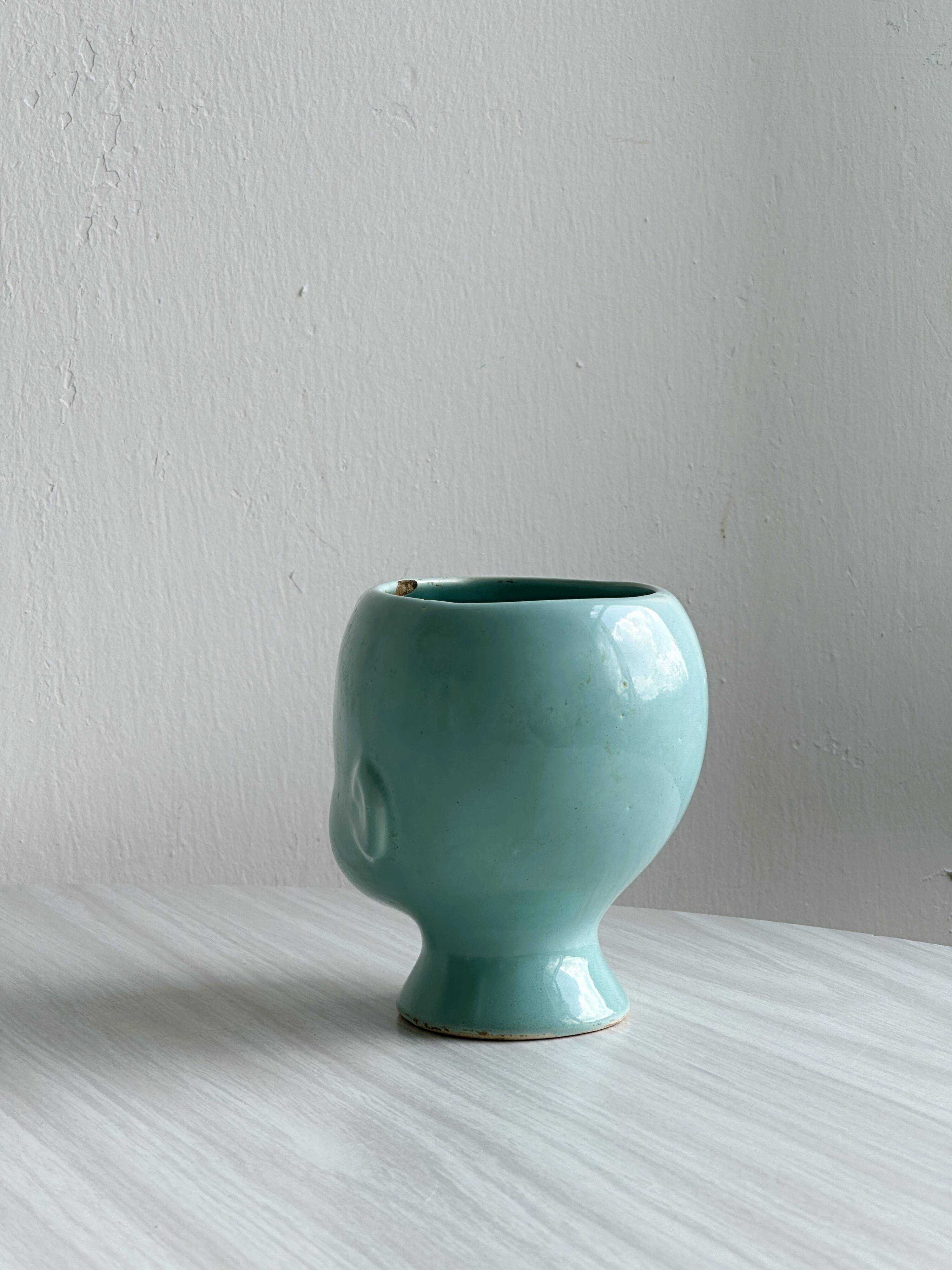 Turquoise plant pot in the shape of a vintage doll's head.