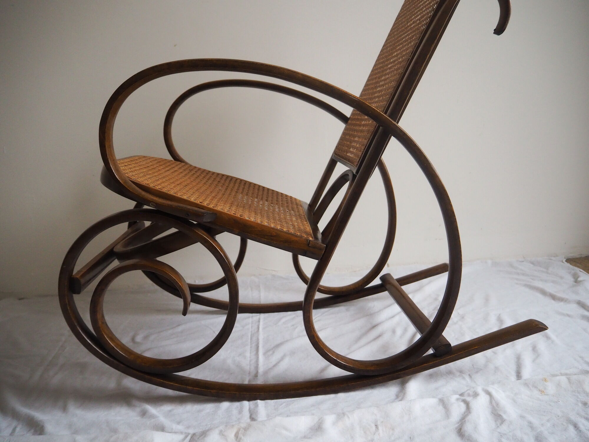 Rocking-chair en bois teinté et assise cannée