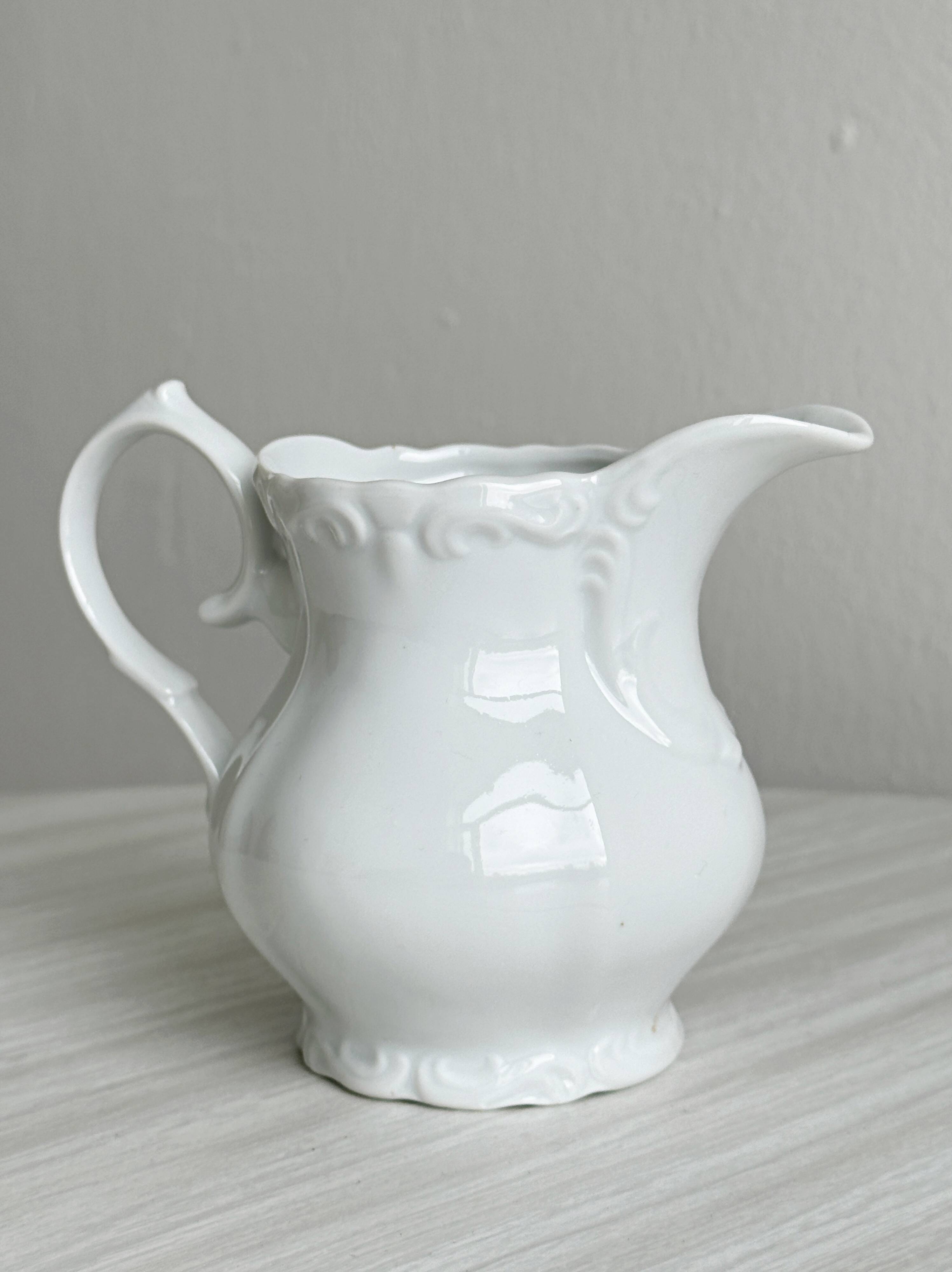 Old white porcelain milk jug, cream jug with relief.
