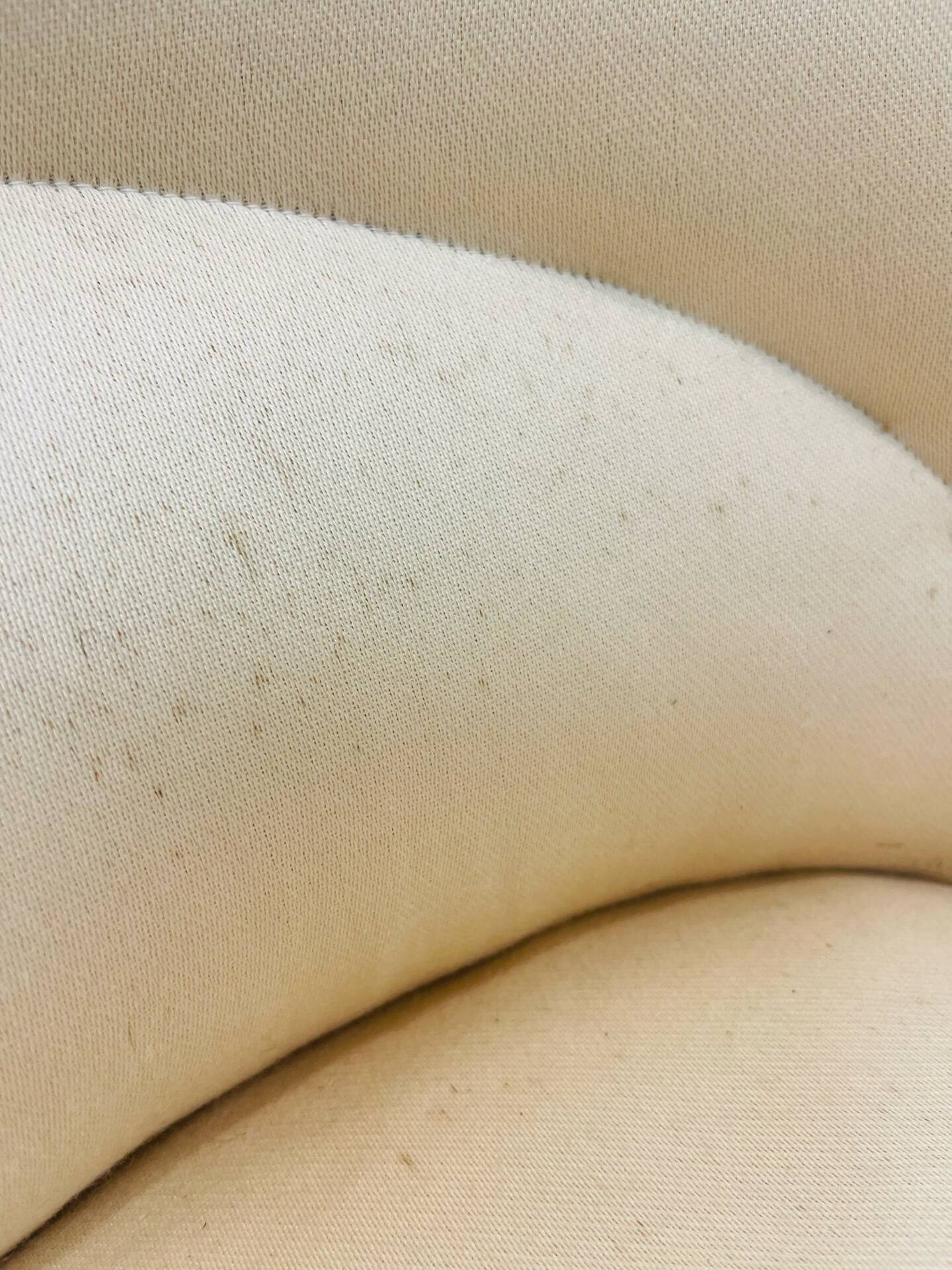 Pale pink upholstered armchair with wooden legs.