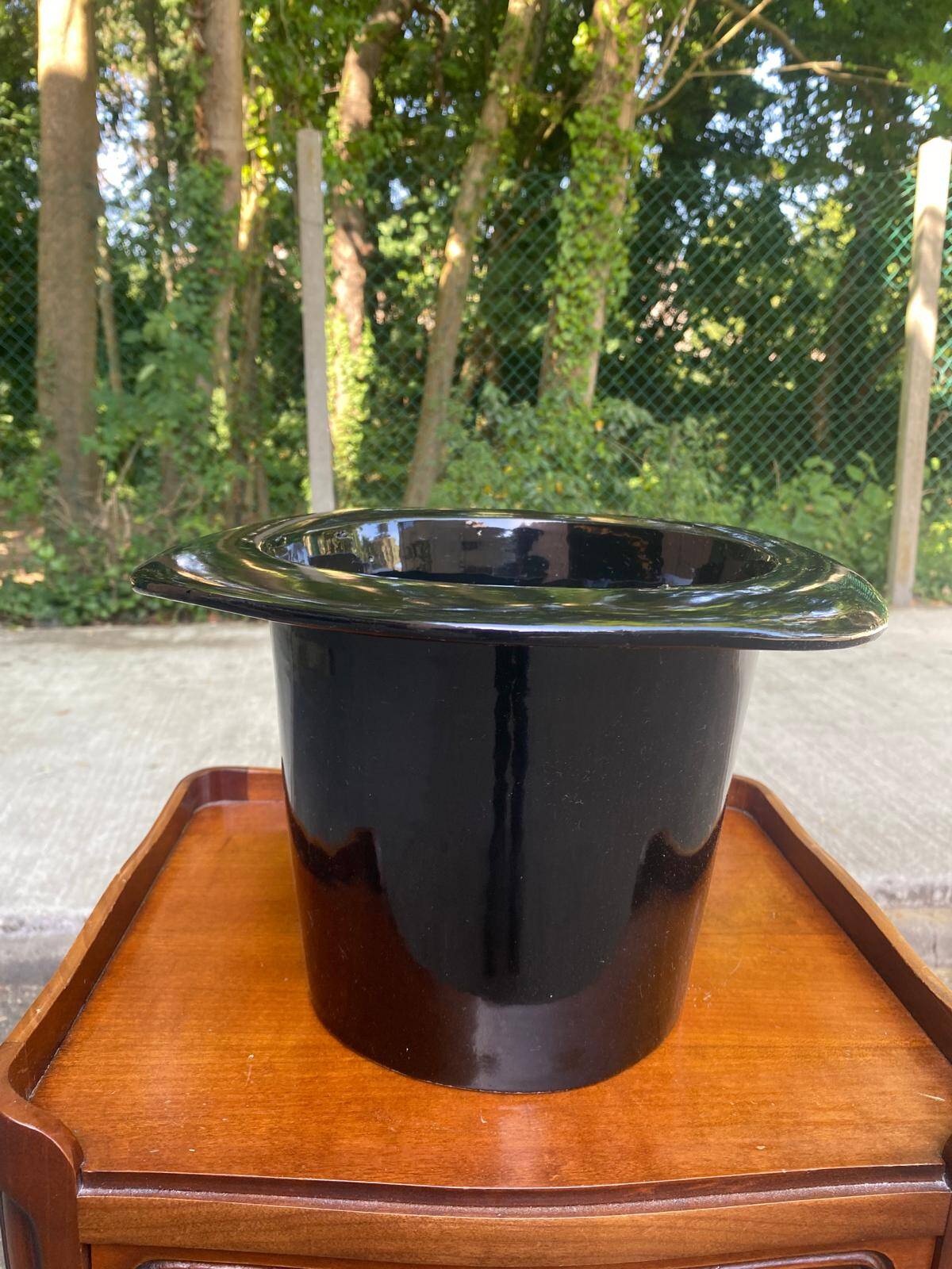 A black top hat-shaped vale turned upside down from the 1960s.