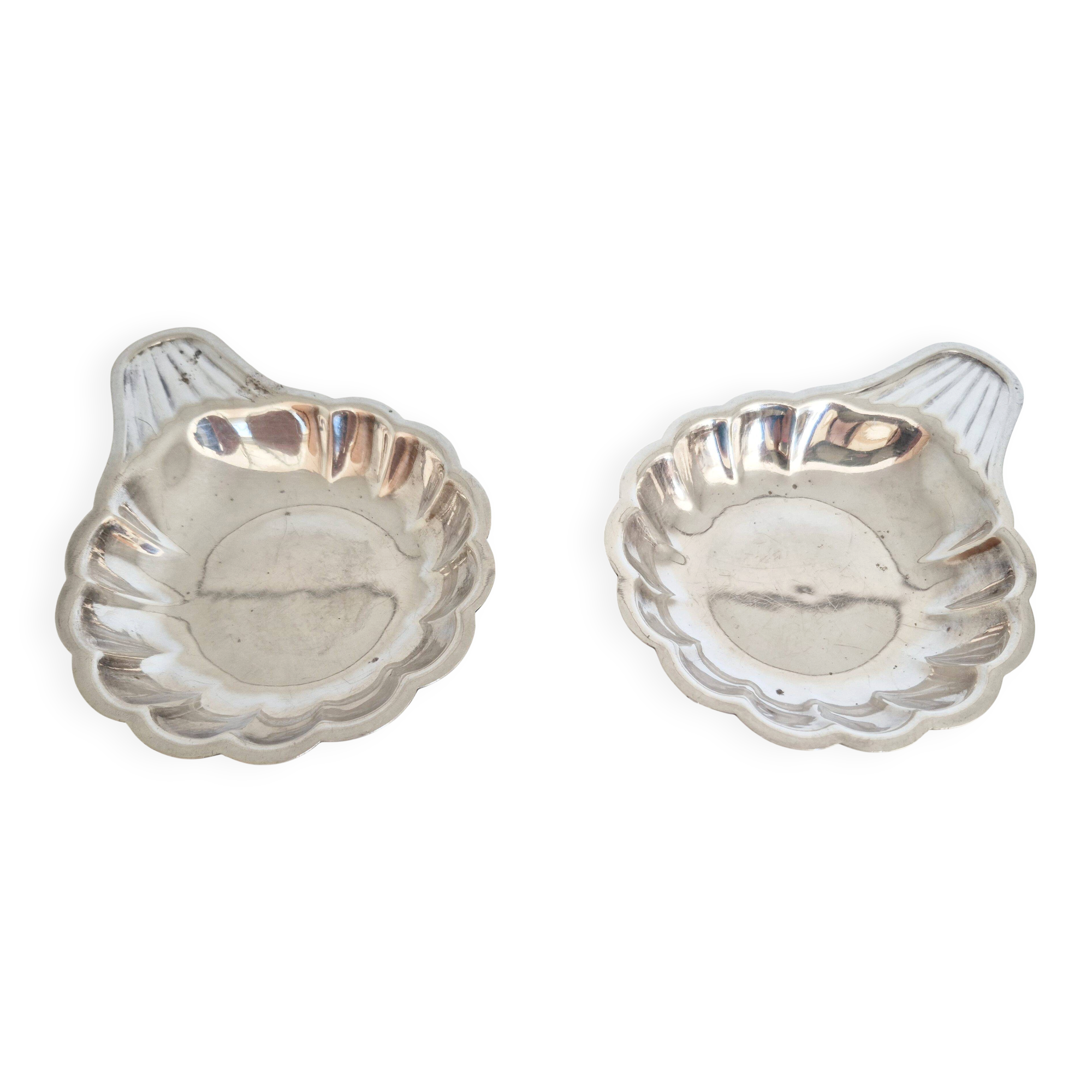 Silver-plated shell-shaped butter dishes, in the shape of a scallop shell.