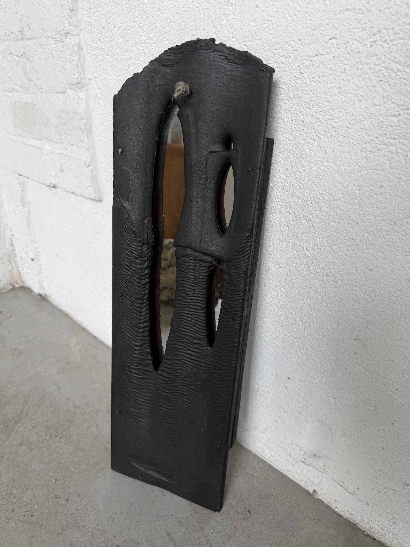 Brutalist hammered mirror, free-form, patinated metal.