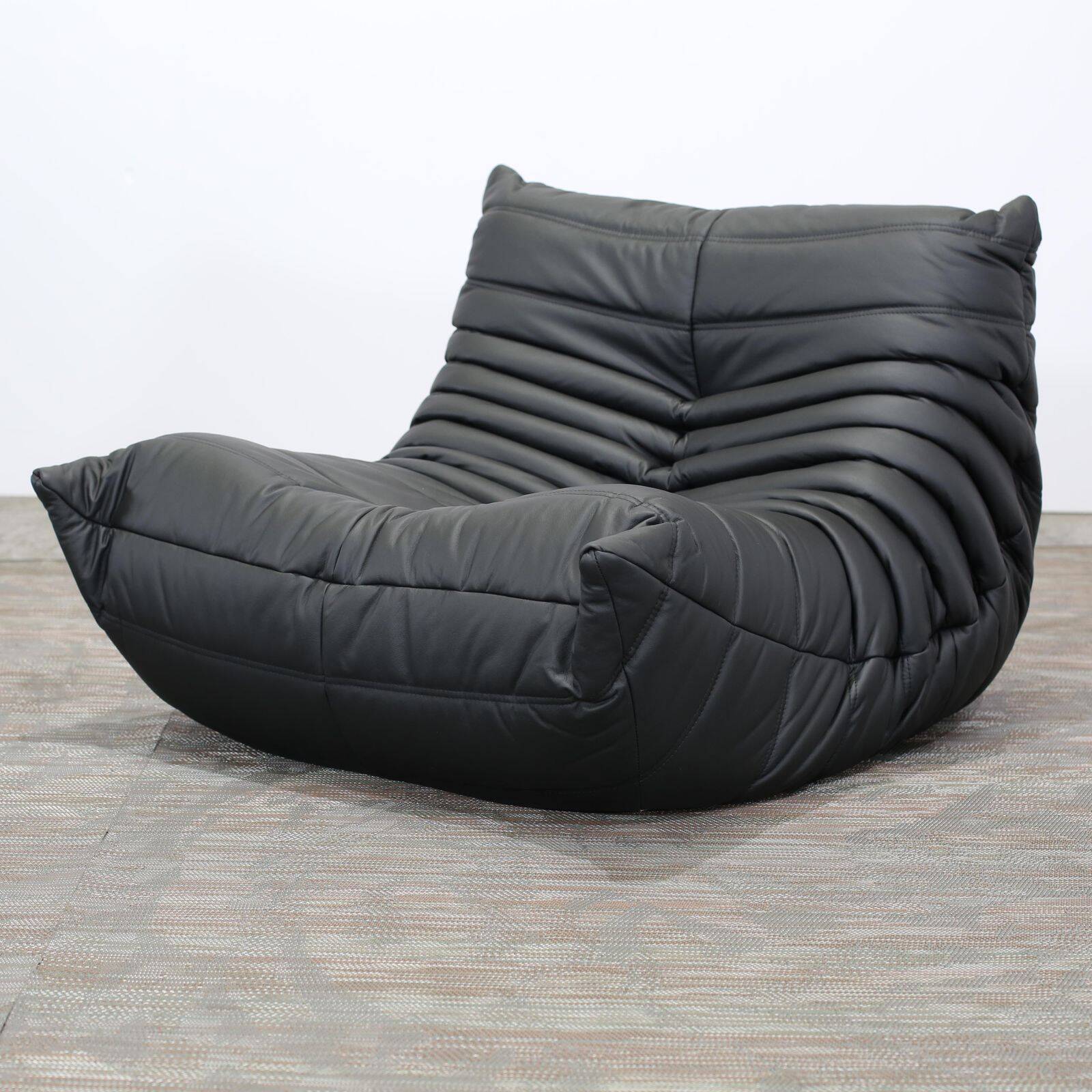 Togo armchair and footrest in black leather by Ligne Roset, designed by Michel Ducaroy.