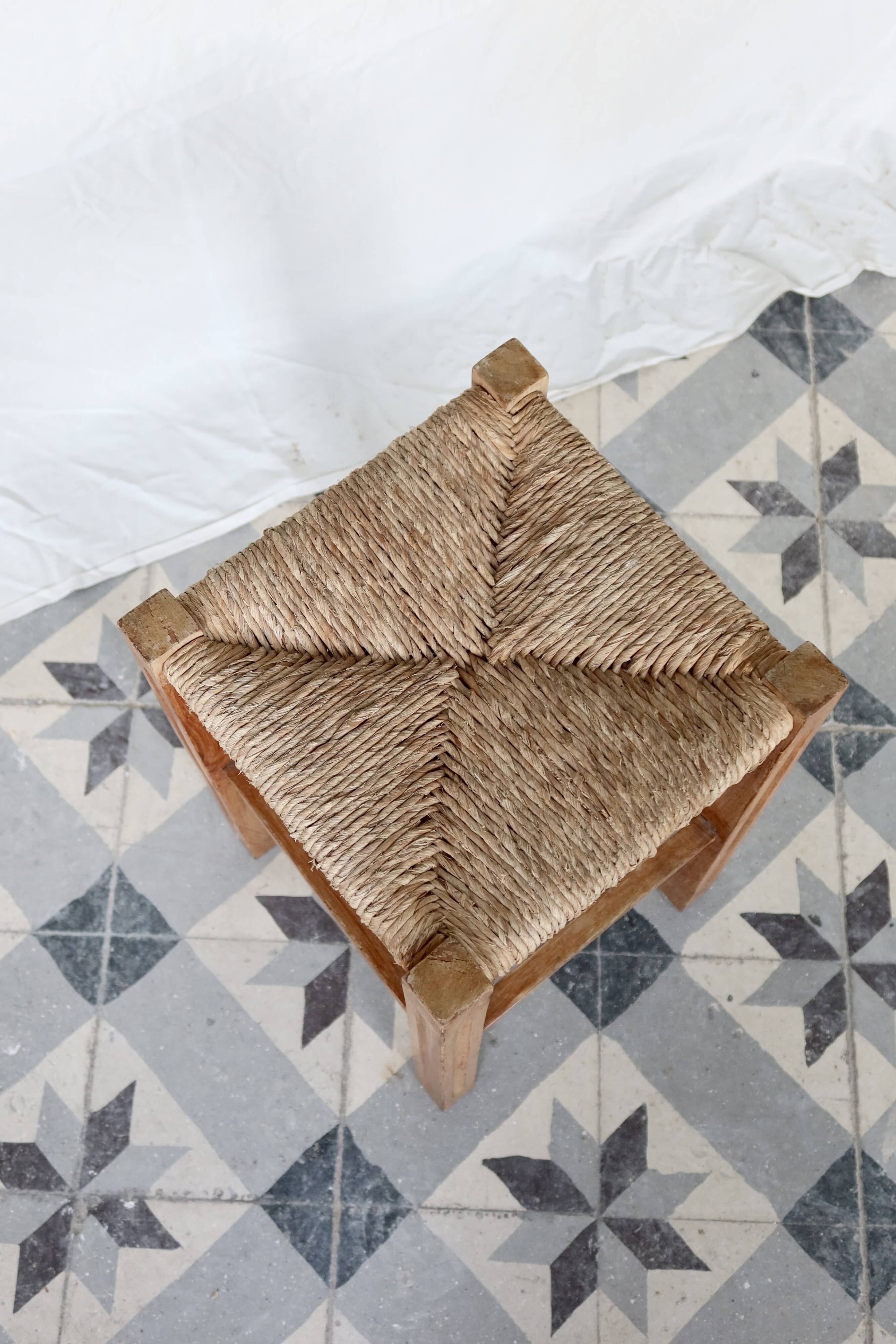 Vintage low stool in rustic style made of wood with a straw seat.