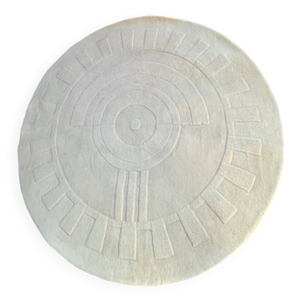 Round ecru rug with geometric relief patterns in wool