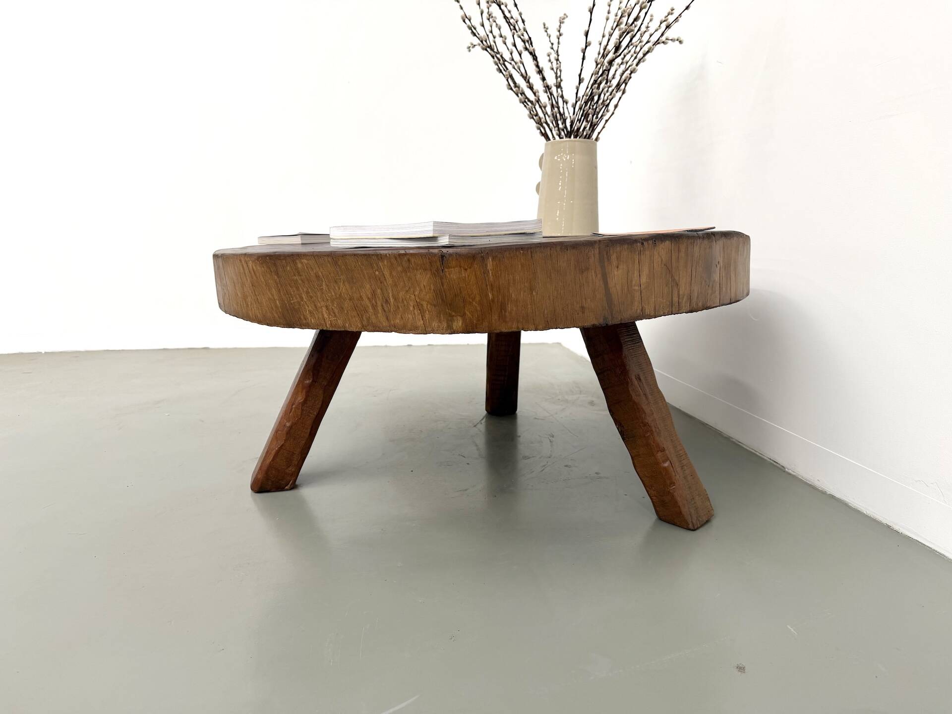 Brutalist coffee table in solid teak, monolithic slab, tripod base.