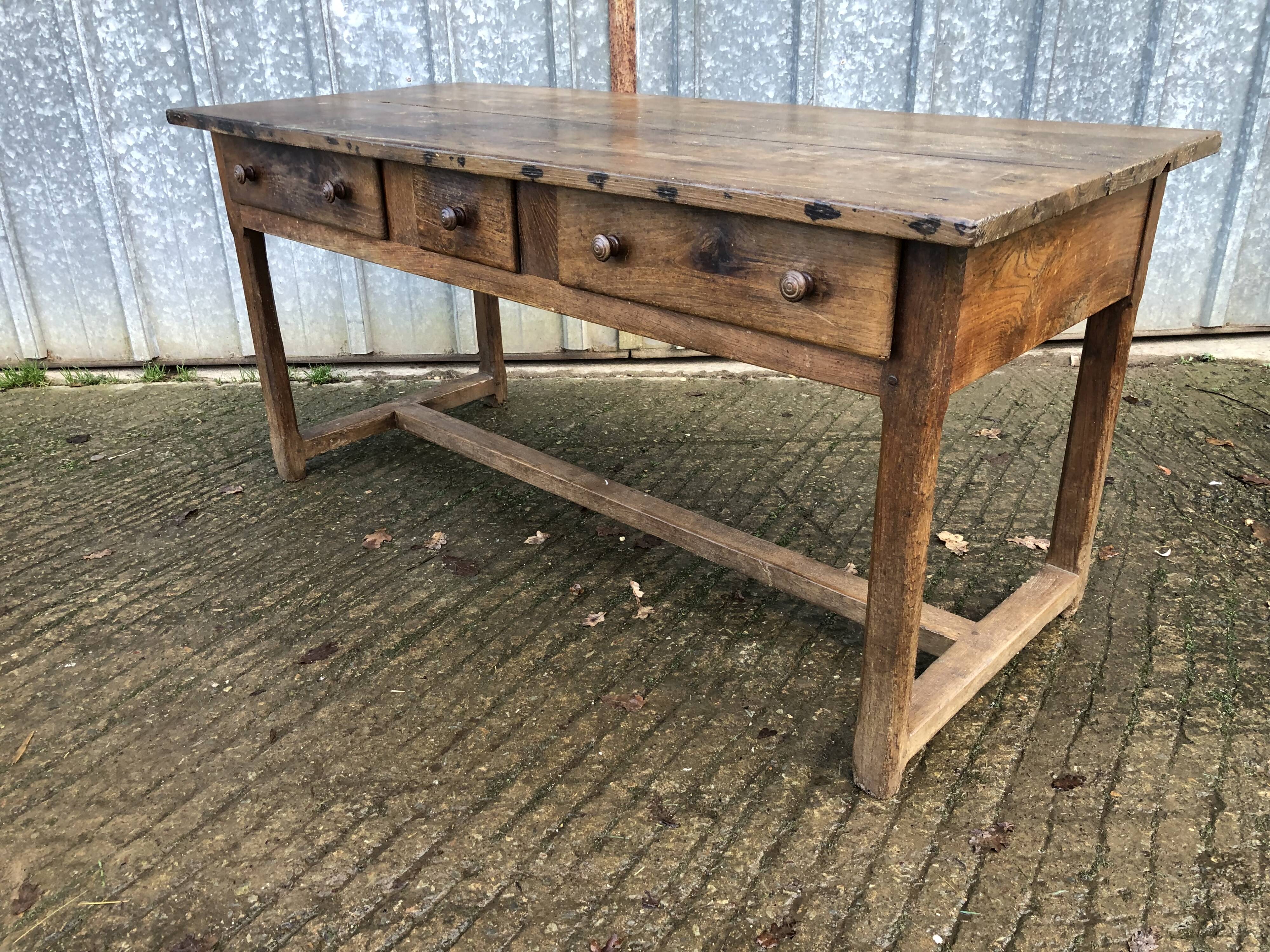 Old chestnut table with 3 front drawers and a cat bar.