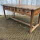 Old chestnut table with 3 front drawers and a cat bar.