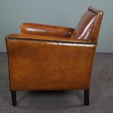 Art deco armchair in sheepskin with black piping and decorative nails