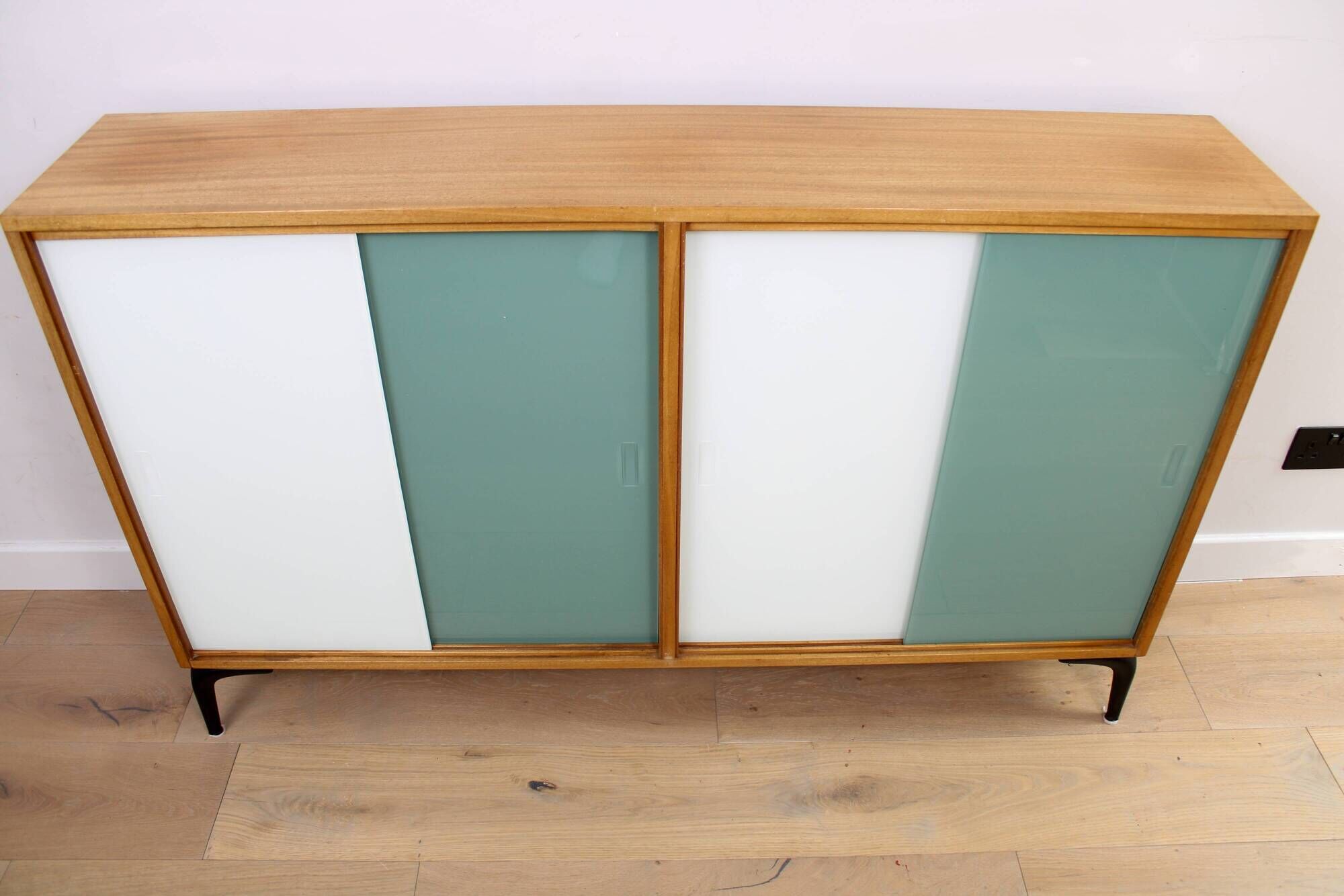 A vintage mid-century bookshelf/sideboard with green and white sliding door