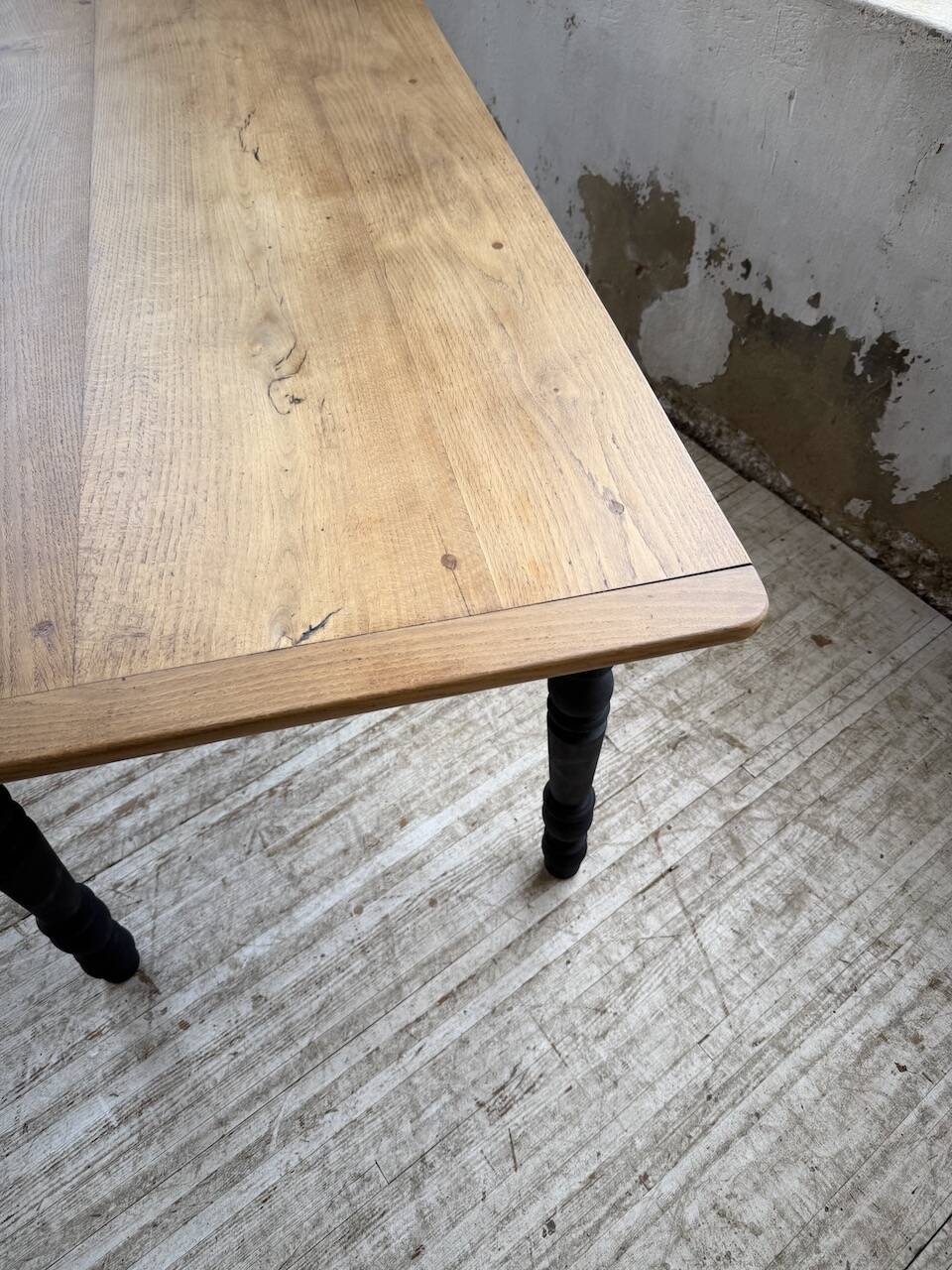Oak farmhouse table with turned black legs.