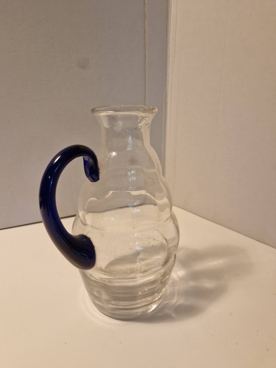 Glass carafe with wavy body and blue handle