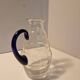 Glass carafe with wavy body and blue handle