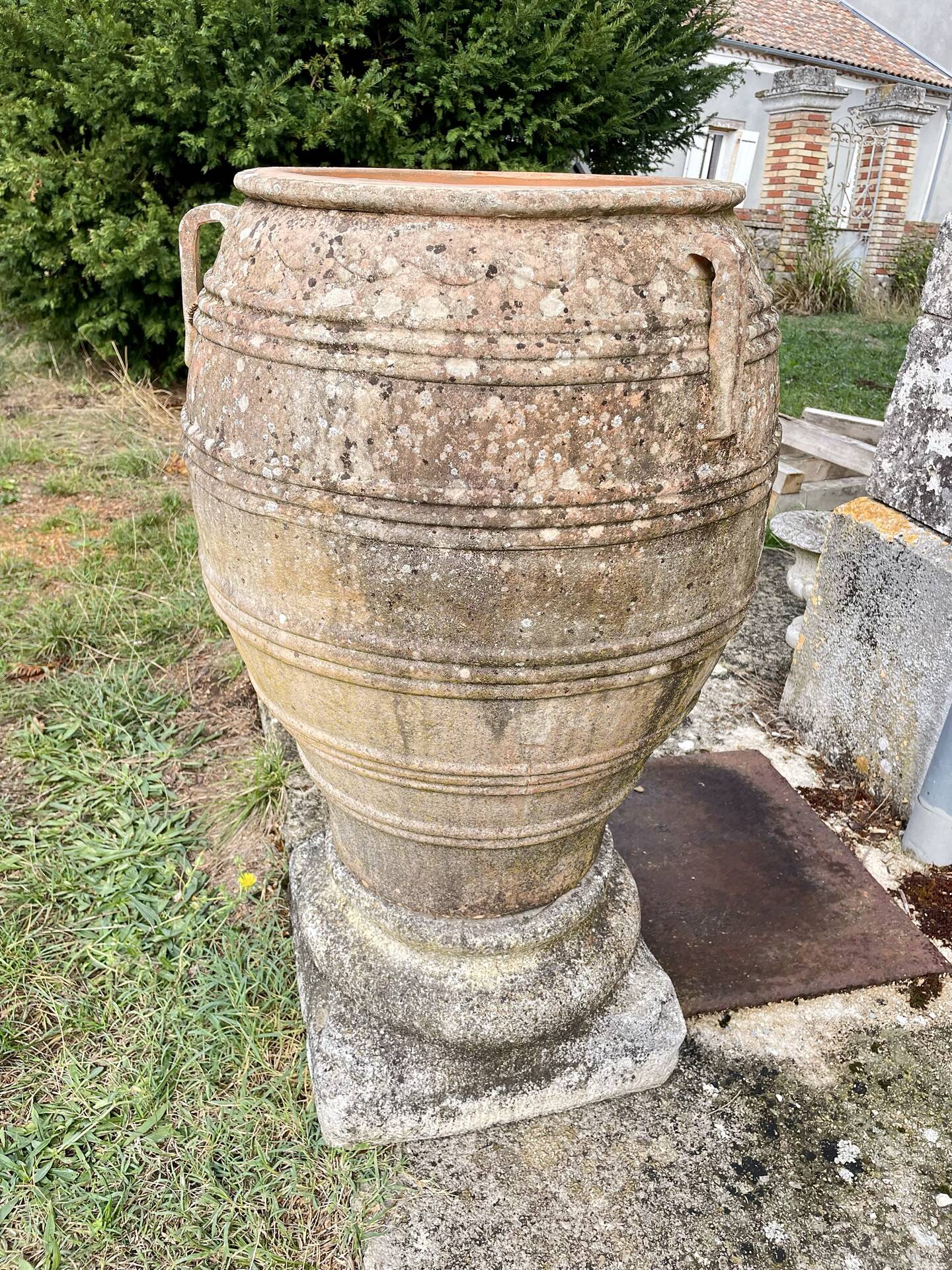 Large Cretan jar in terracotta with three handles on a stone base.