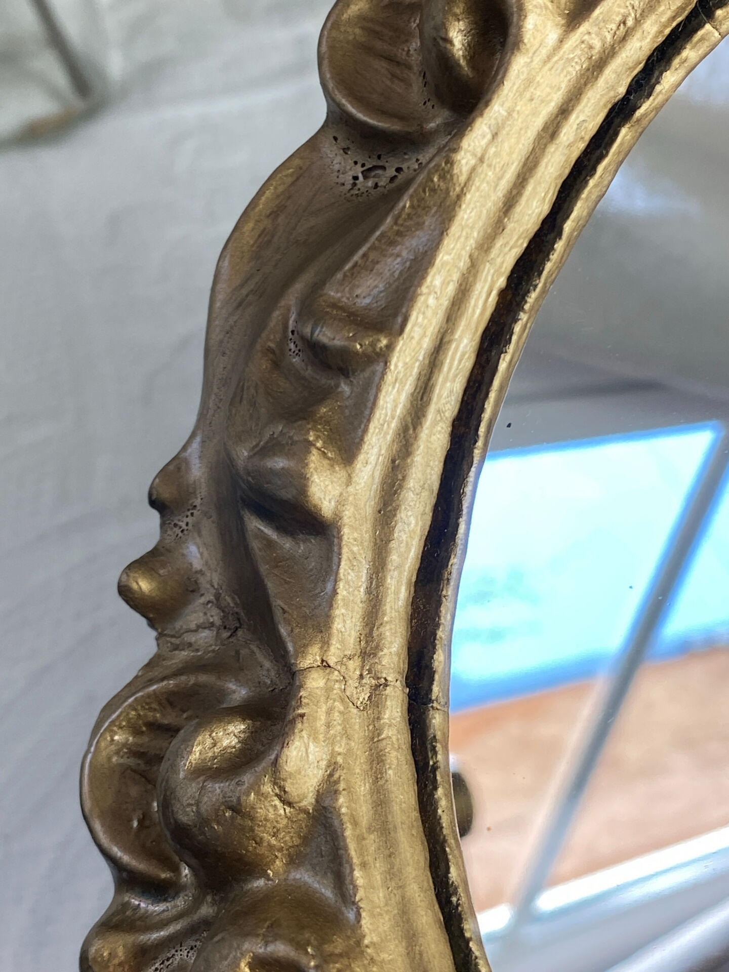 Round wooden mirror in golden colour.