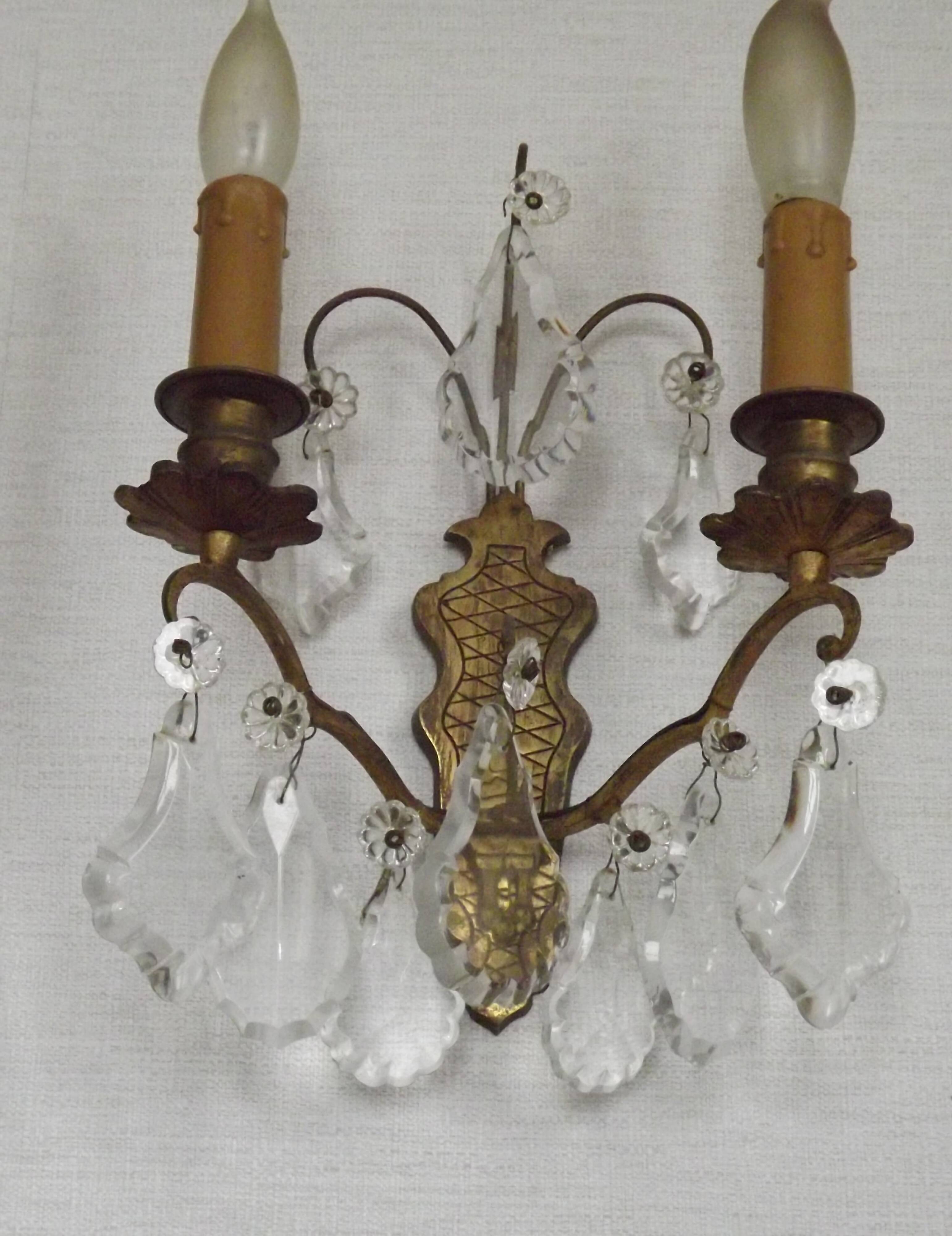 Pair of French antique brass double wall lights with assorted crystals.