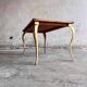 Table basse vintage avec pieds dorés et plateau incrusté de motifs géométriques en placage de bois brun clair