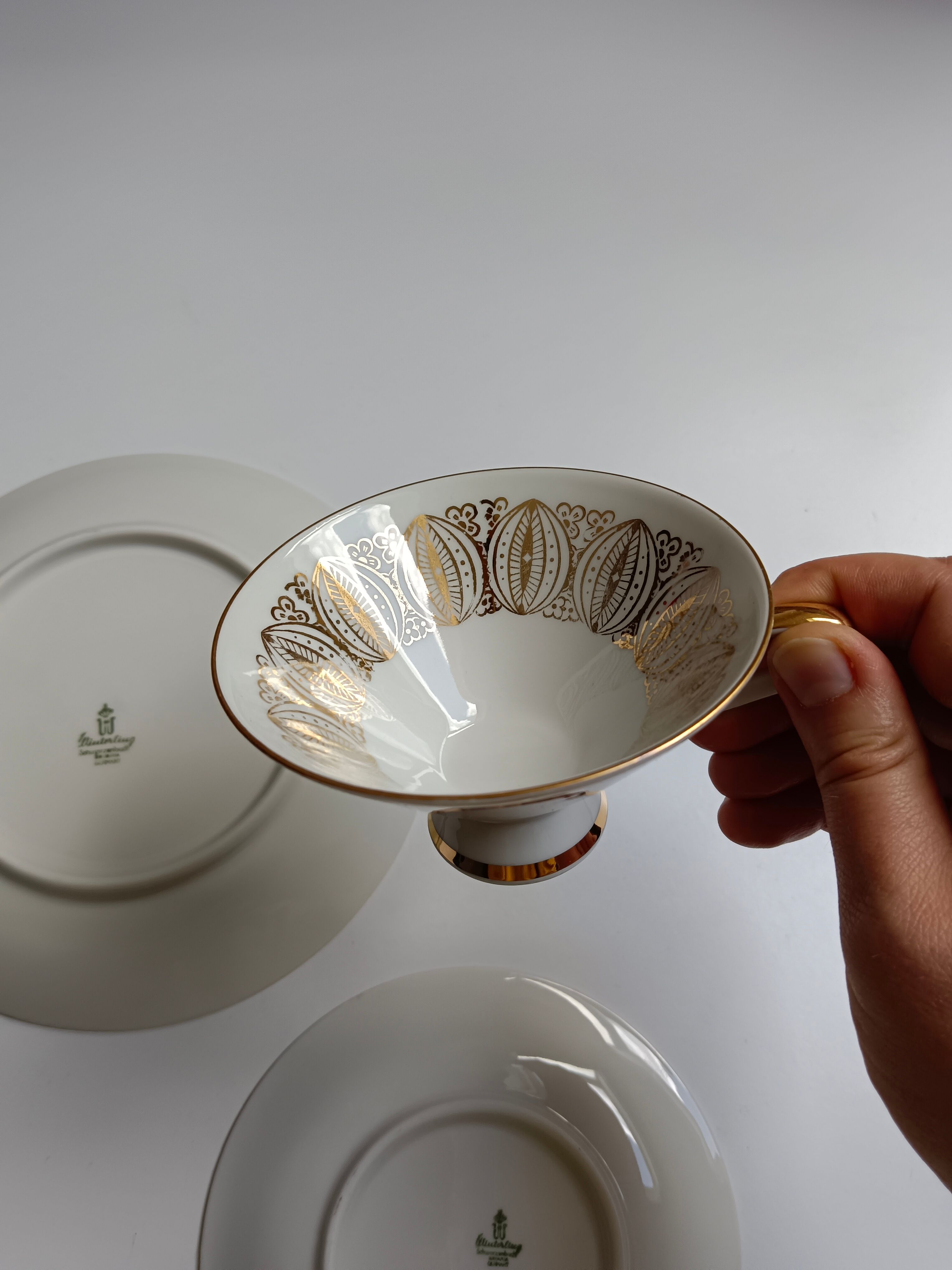 Solitaire tea cup, saucer, and dessert plate in white and gold.