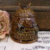 Honey pot in the shape of a hive decorated with bees.