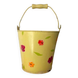 Small metal bucket with floral print on a yellow background