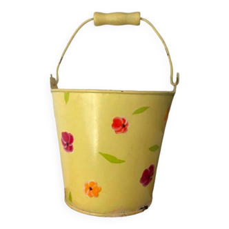 Small metal bucket with floral print on a yellow background