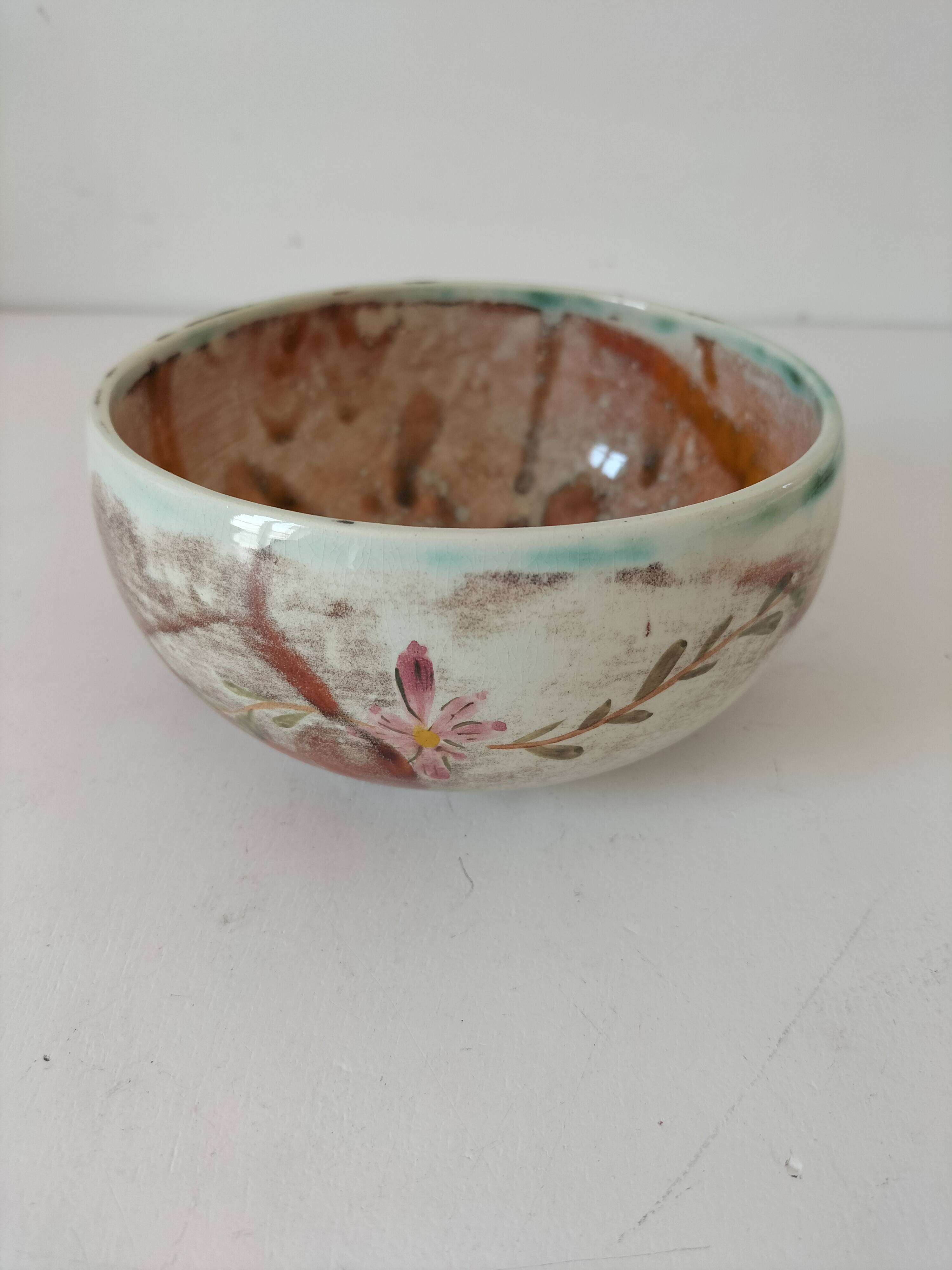 Red-orange glazed ceramic workshop bowl with floral decoration.