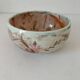 Red-orange glazed ceramic workshop bowl with floral decoration.