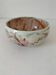 Red-orange glazed ceramic workshop bowl with floral decoration.