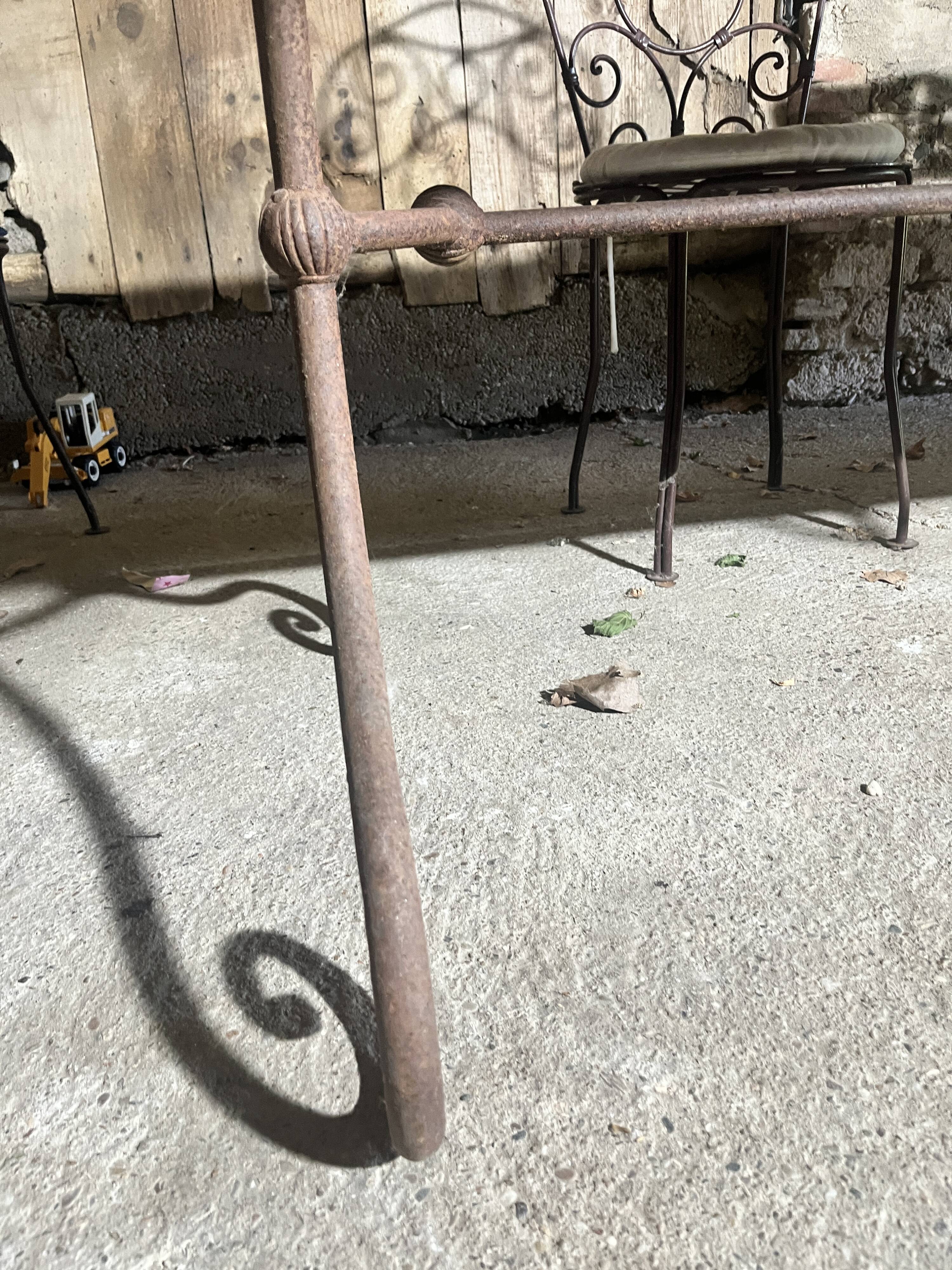 Old wrought iron table and its armchairs and chairs for outdoor use.