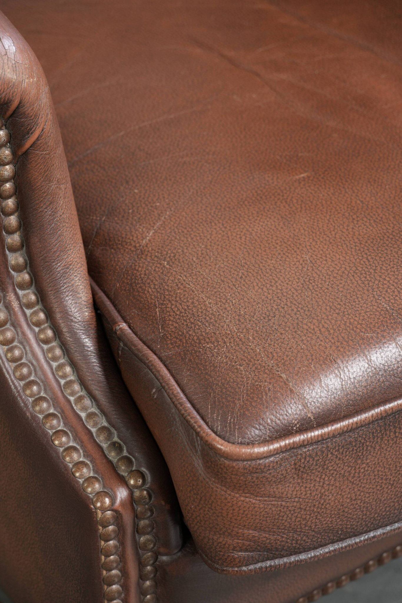 Fauteuil à oreilles en cuir de vache confortable de style anglais avec un look intemporel.