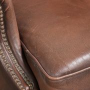 Fauteuil à oreilles en cuir de vache confortable de style anglais avec un look intemporel.