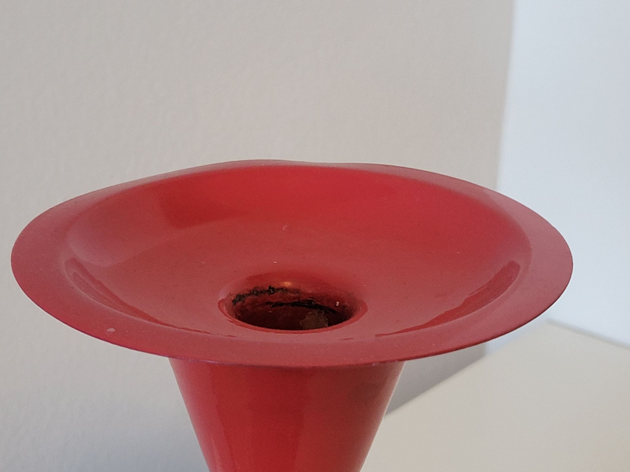 Vintage design candlestick in red metal in the shape of an hourglass