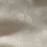 Damask tablecloth with a floral pattern and a central embroidered monogram.