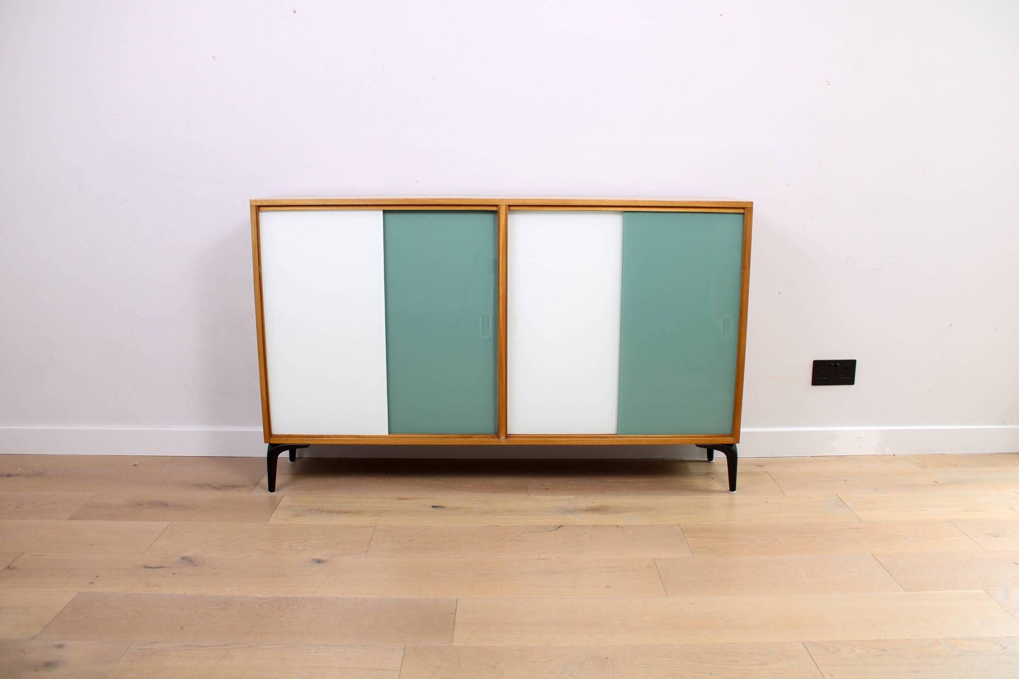 A vintage mid-century bookshelf/sideboard with green and white sliding door