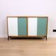 A vintage mid-century bookshelf/sideboard with green and white sliding door