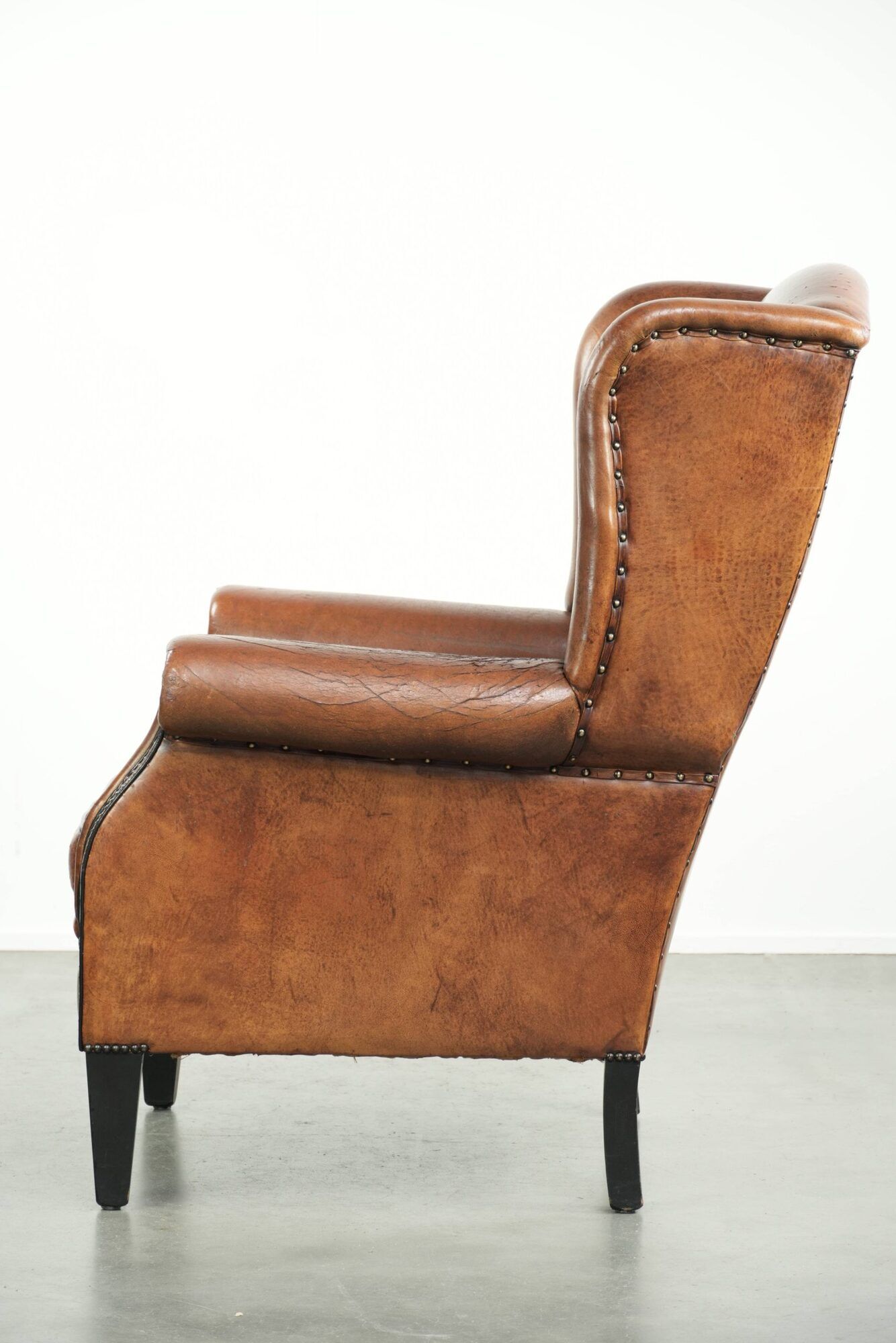 Sheepskin wingback armchair finished with black piping and a correct seat