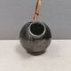 A ceramic jug with a metallic glaze and a handle made of woven raffia.