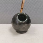 A ceramic jug with a metallic glaze and a handle made of woven raffia.