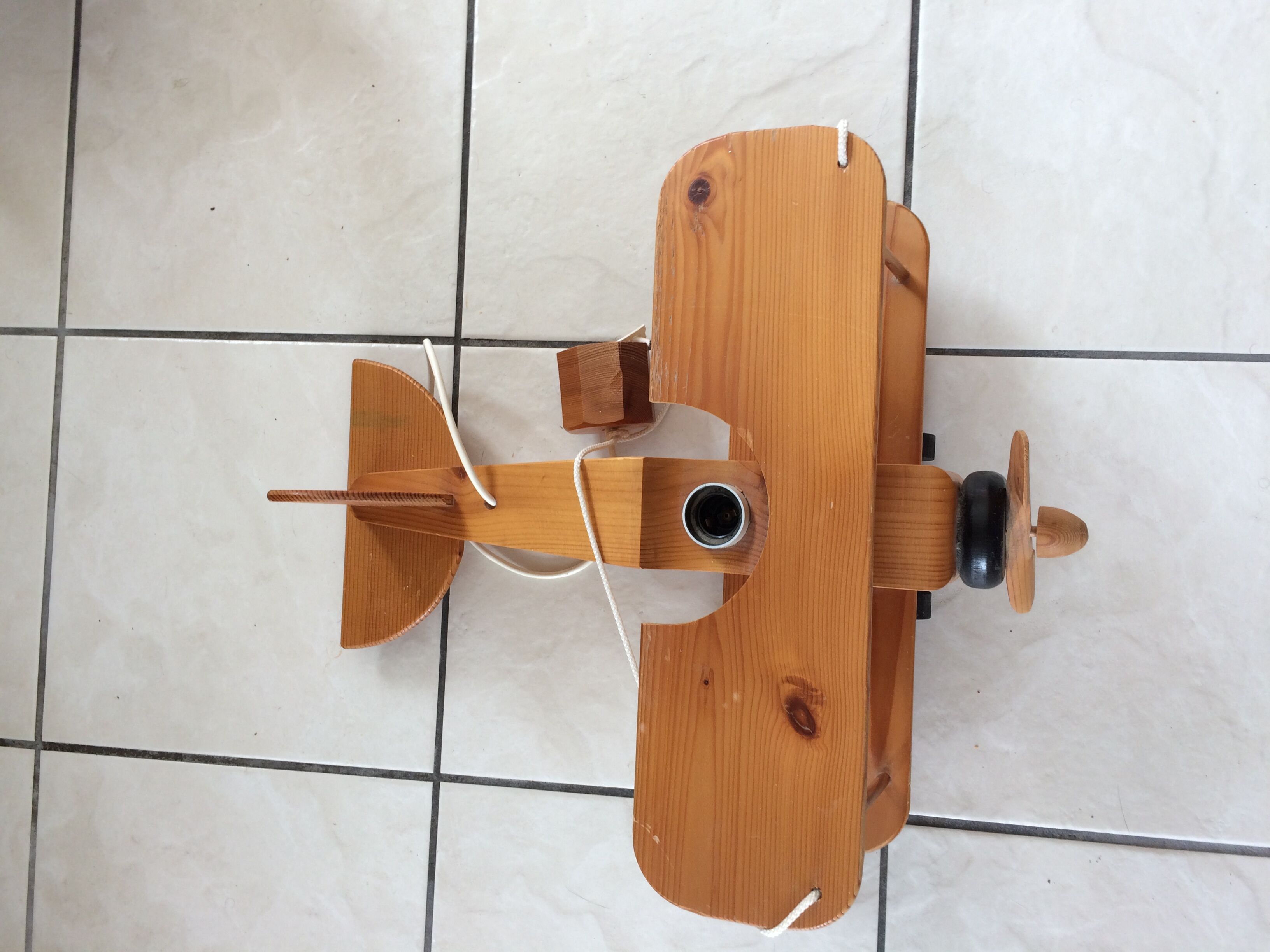 Light wood hanging in the shape of an airplane. Electric.Year 70.