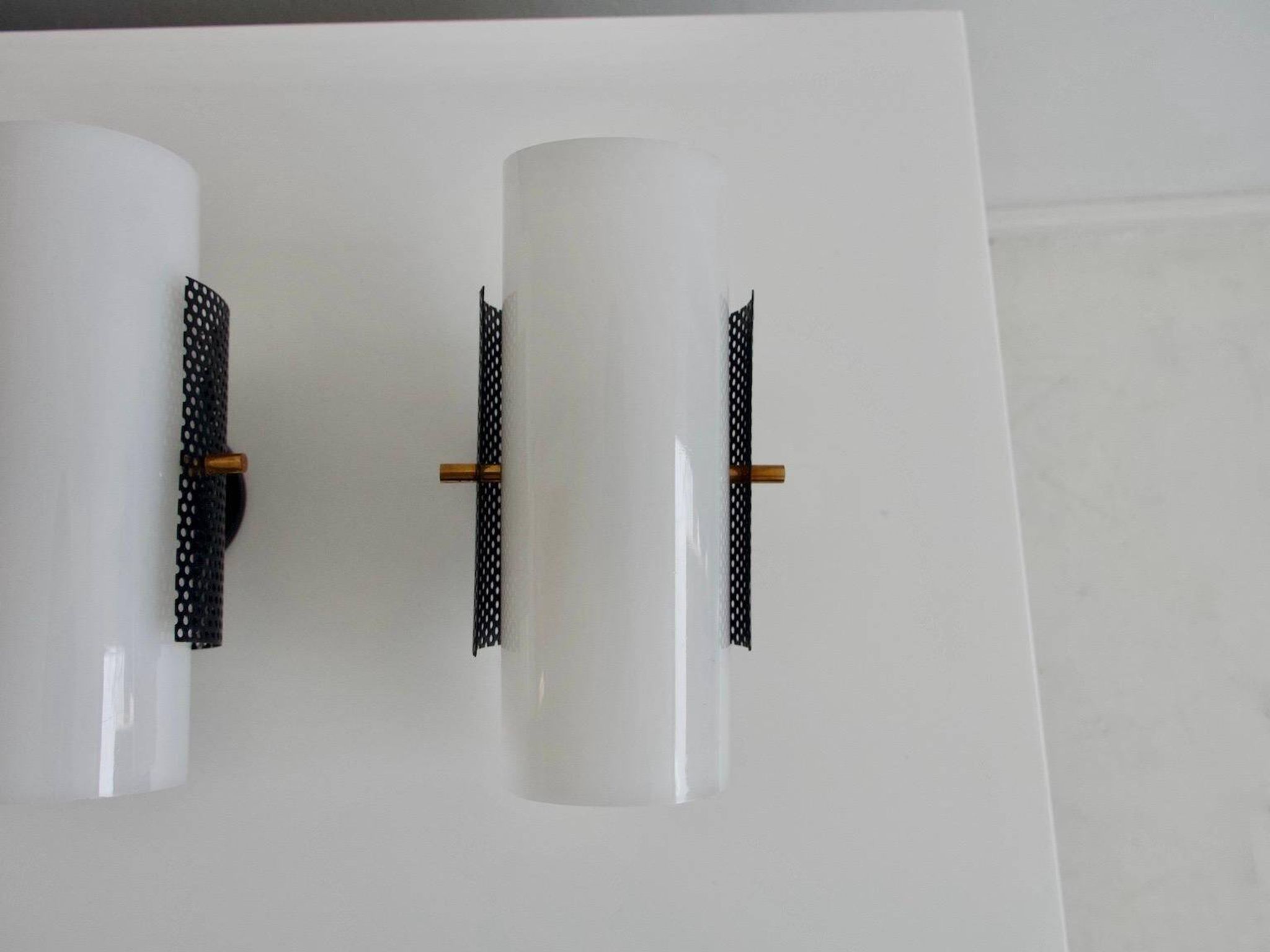 Set of four wall lights in white plexiglass and perforated black metal.