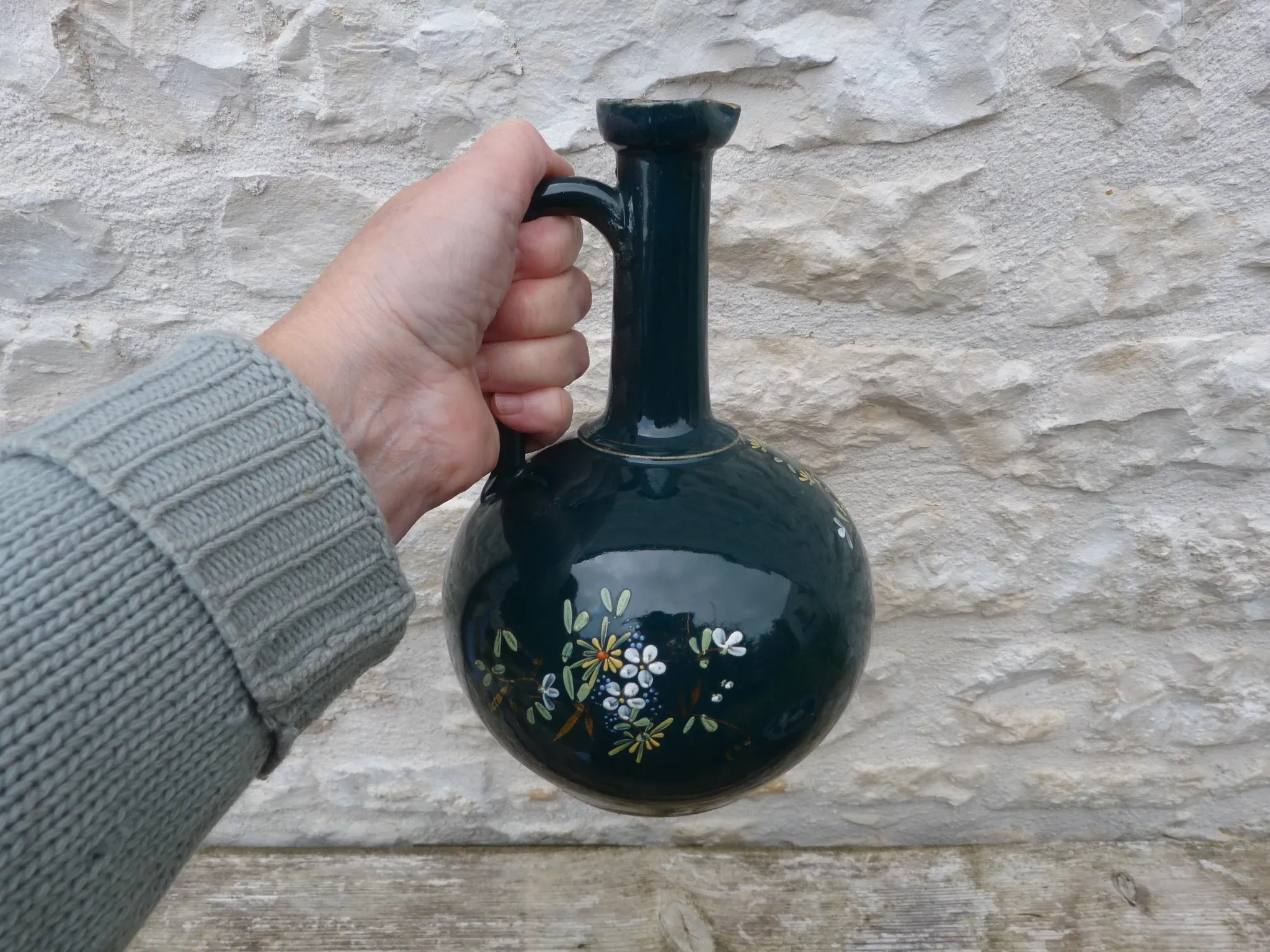 Old ceramic jug with flowers or single-stem vase.
