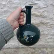 Old ceramic jug with flowers or single-stem vase.