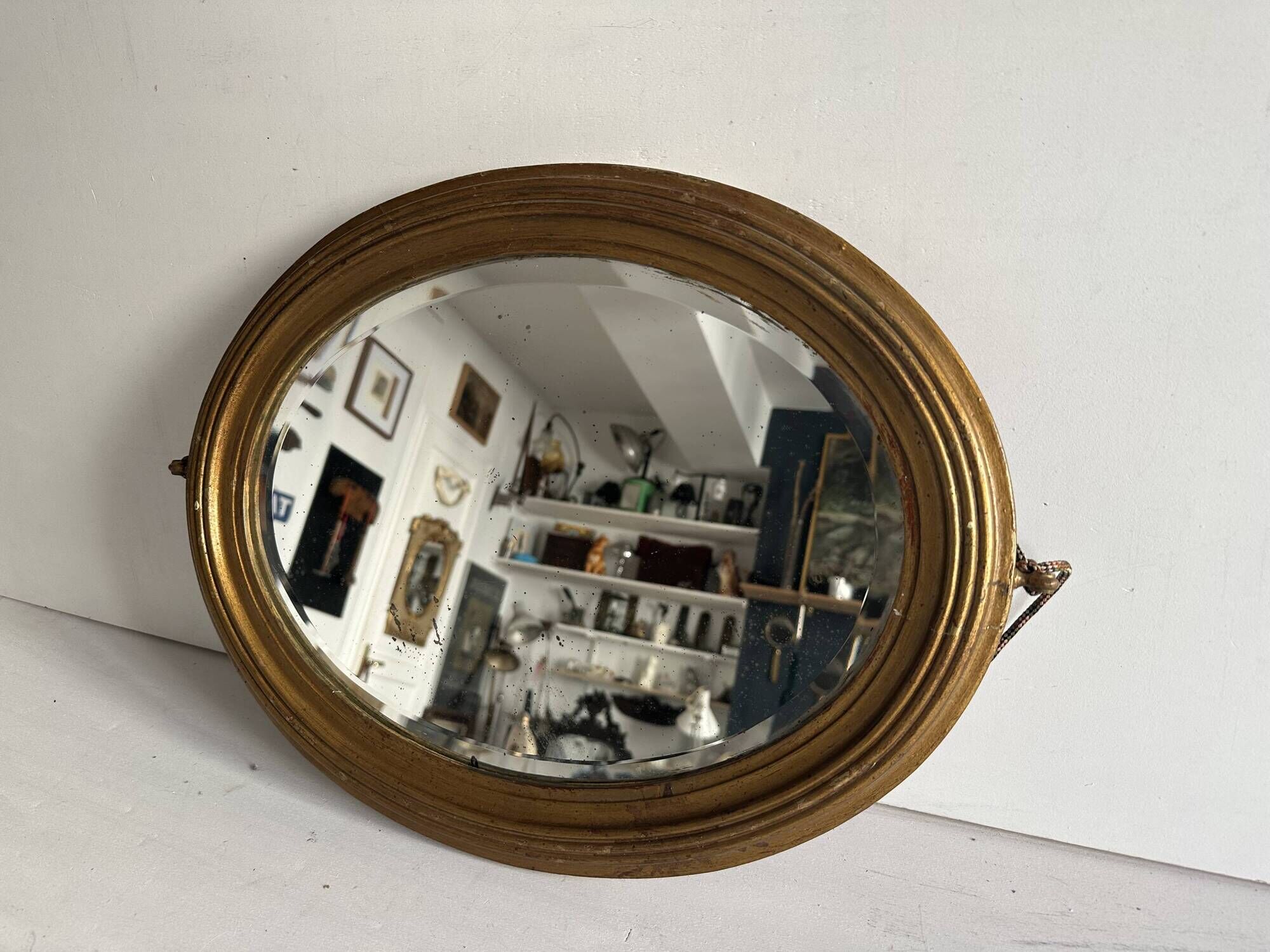 Antique oval mirror in gilded wood, bevelled mercury glass, 19th century.