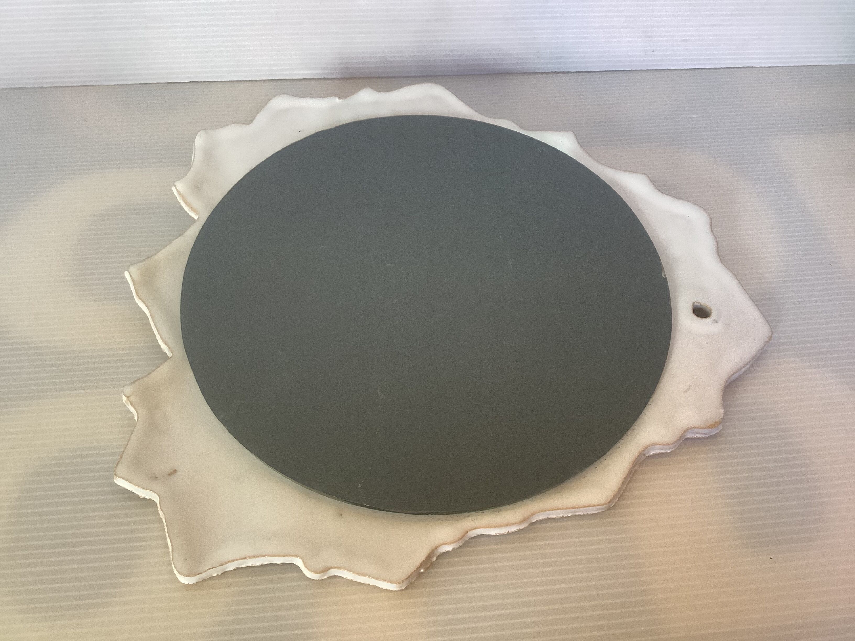 Ceramic mirror with serrated edge and a flower