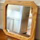 Octagonal mirror in light wood with grooves.